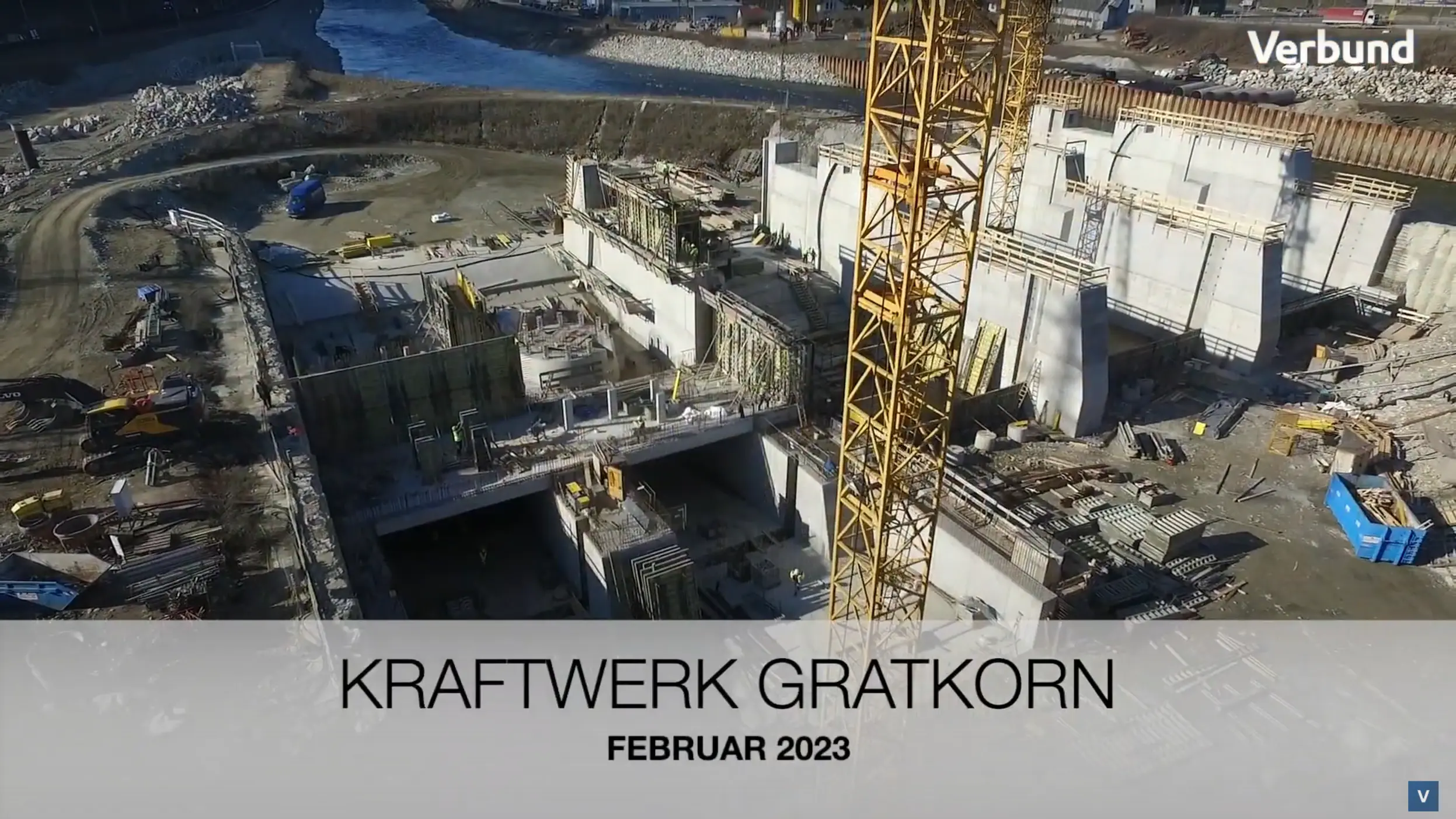 Vorschaubild für das Video zeigt den Betonbau am Murkraftwerk Gratkorn im Februar 2023. Zu sehen ist eine Drohnenaufnahme der Baustelle mit einem großen Kran, halb-fertigen Betonstrukturen, Baumaschinen und Arbeiter*innen im Einsatz.