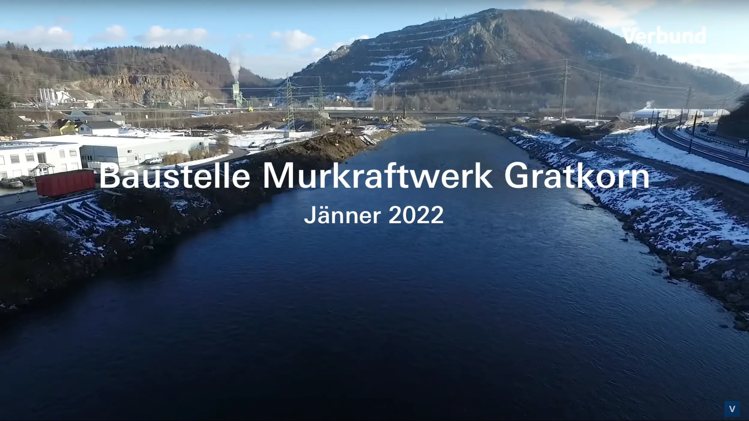 Vorschaubild zeigt den Beginn der Bauarbeiten am Murkraftwerk Gratkorn im Januar 2022. Eine Drohnenaufnahme enthüllt die winterliche Landschaft entlang des Flusses Mur mit Schnee bedeckten Bereichen, der Baustelle und angrenzenden Gebäuden im Hintergrund.