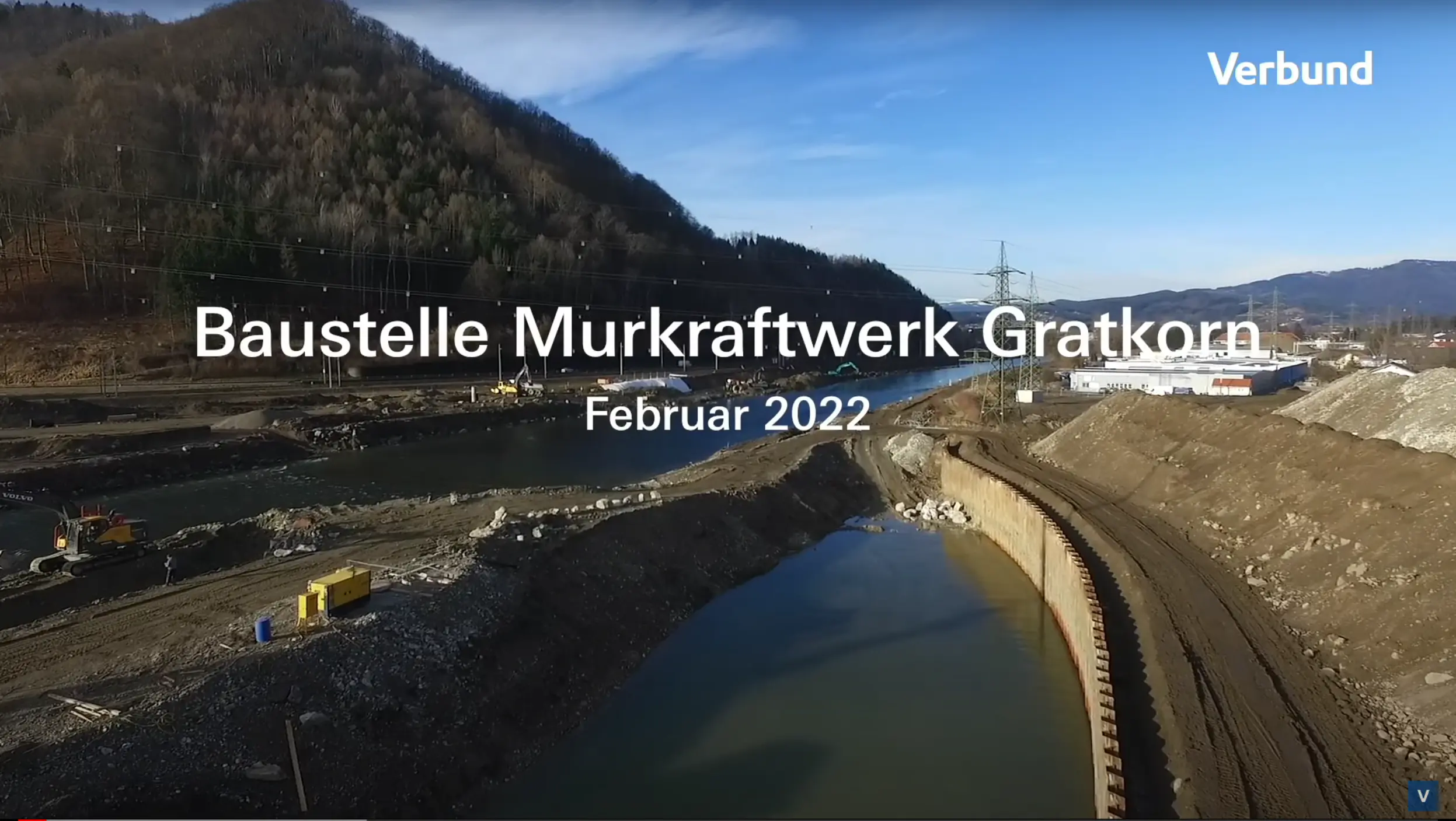 Vorschaubild zeigt eine Luftaufnahme der Baustelle Murkraftwerk Gratkorn im Februar 2022. Sichtbar sind die frühen Phasen der Baustelle mit ausgehobenen Bereichen für die Fundamente, Baufahrzeugen und dem Fluss Mur, der sich durch die Szene schlängelt.