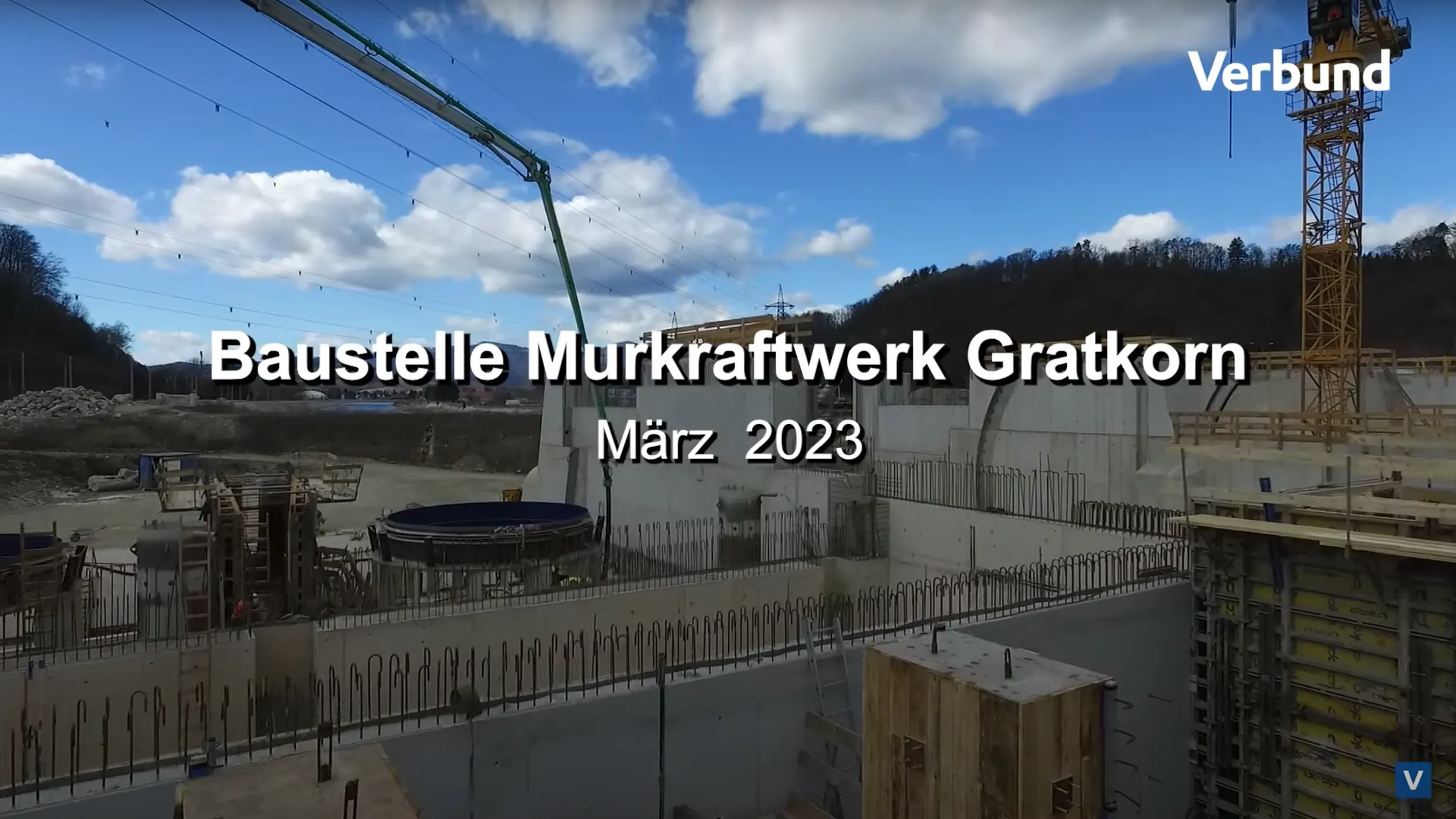 Vorschaubild für das Video zum Baufortschritt der Baustelle Murkraftwerk Gratkorn im März 2023, zeigt Betonbauwerke, eine aktive Baustelle mit einem Kran und heiterem Himmel im Hintergrund.